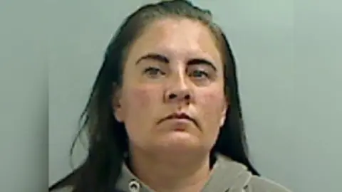 Cleveland Police A woman with long dark hair and dark eyebrows looks at the camera in a police mugshot. She is wearing a grey hoodie.