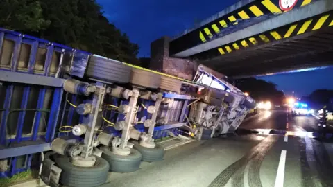 Leicestershire Police A lorry on its side on the A5 after hitting the Watling Street bridge in June 2022.
