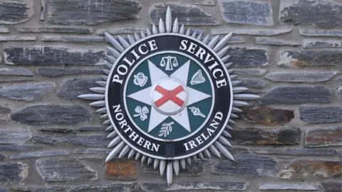 PA Police Service of Northern Ireland crest hanging on stone wall in Londonderry