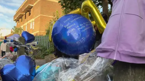 A blue balloon with "I hope you rest in eternal peace" written on the side