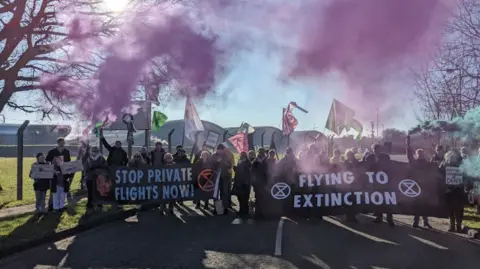 Protesters with colourful flares blocking the entrance to the airport.