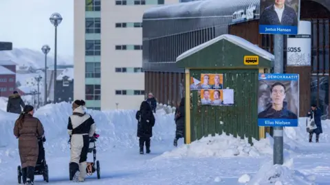 Imagens cartas conversam com duas mulheres com empurrões, eles mostraram pôsteres de várias campanhas de seleção para caminhar ao lado de um ponto de ônibus, neve no chão ao redor