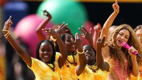 Ghetto Kids and Shakira smile as they perform together at the World Cup final's halftime show.
