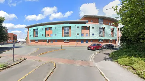 Google Google Streetview photo of the block of flats on St Georges Parade in Wolverhampton. Built around a tight corner in the road, the two to four-storey flats are built from red brick with light blue cladding