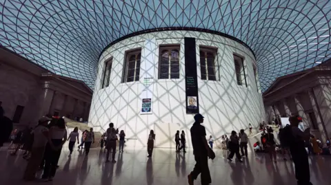 EPA Crowds of people explore the main hall of the British Museum, they are shadowed and the image is taken from a low angle.