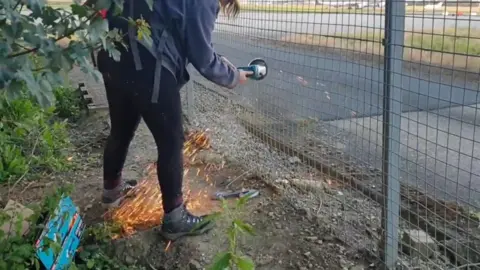 Just Stop Oil  A person cutting through a fence at Stansted Airport using a grinder