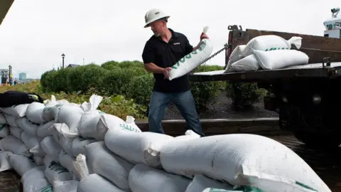 A man puts sandbags in front of a door