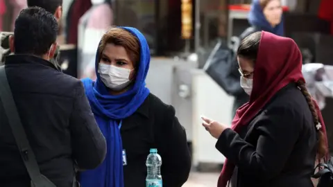 EPA Women wearing face masks stand in a street in Tehran, Iran (26 February 2020)