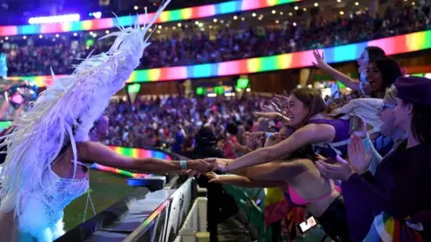 EPA A woman taking part in parade leans in and touches hands with spectators