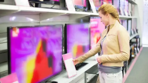 Getty Images A woman looking at flat-screen TVs