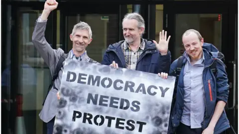 PA Media Dr Larch Maxey, Extinction Rebellion's co-founder Roger Hallam and Michael Lynch-White outside Isleworth Crown Court in London, after they received a suspended sentence, for allegedly trying to shut down Heathrow Airport with small toy drones in September 2019.