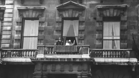 Getty Images 27th June 1927: George, Duke of York and Elizabeth, Duchess of York acknowledging the cheers of a crowd from the balcony of their home at 145 Piccadilly