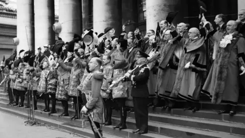 Getty Images Heralds and City dignitaries cheering the Queen at the Royal Exchange on 8 February 1952