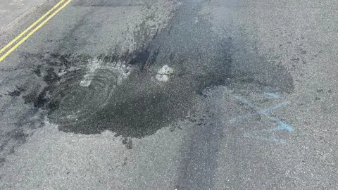 View of the dip in Cromer Road showing a blue painted X and a wet patch.