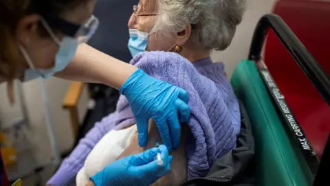 Reuters A woman receives the first of two Pfizer/BioNTech COVID-19 vaccine jabs, at Guy"s Hospital