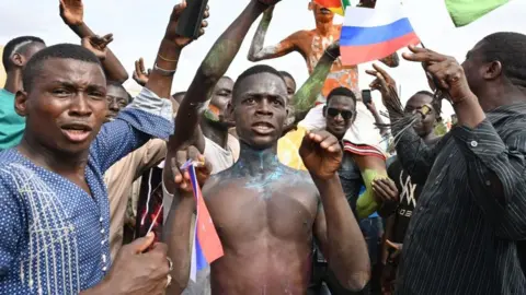 Getty Images Supporters of Niger's National Council for the Safeguard of the Homeland (CNSP) wave Niger and Russian flags as they demonstrate in Niamey on August 6, 2023