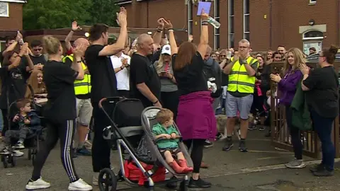 BBC Crowd raise arms at the start of the walk