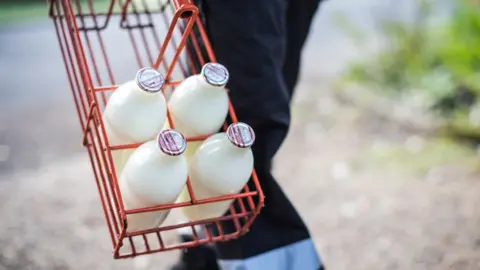 Milk & More Milk bottles being carried by a milkman