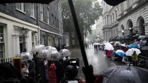 Victoria Jones/PA Wire People wait in the rain in Downing Street