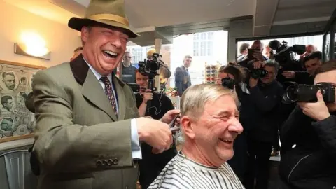 PA Nigel Farage cutting man's hair during campaign visit to Shoreham