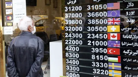 EPA A man checks currency exchange rates in Tehran, Iran (14 October 2020)