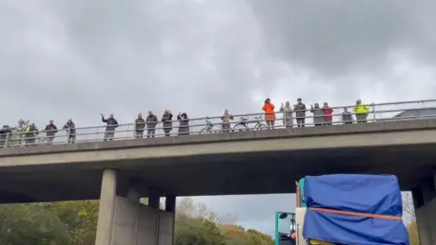 Suffolk Highways People gather on an overpass and wave at an abnormal load.