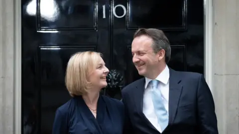 PA Media Liz Truss and husband smile on doorstep of No 10