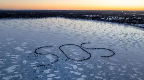 Getty Images In an aerial view, demonstrators spell out an SOS signal of distress on a frozen Lake BdeMaka Ska on January 30, 2026 in Minneapolis, Minnesota
