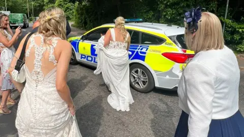 Jemma and Sian Batchelor-Thomas Jemma and Sian Batchelor-Thomas approaching the police car in their wedding dresses