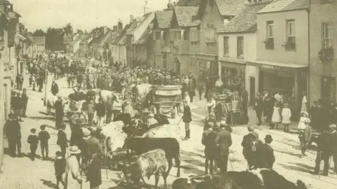 Explore Wiltshire A historical photo of a crowded cattle market on Cricklade High Street