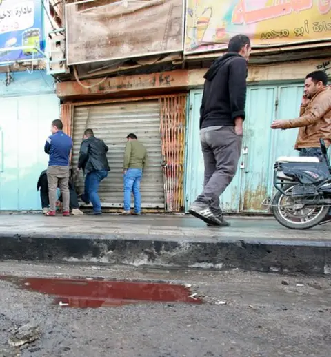 EPA Men pass a bloodstained puddle on Tayaran Square, Baghdad, 15 January