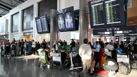 Reuters Passengers standing in front of departures boards at Muscat Airport