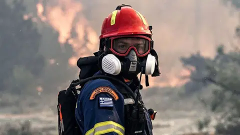 Getty Images A firefighter looks on during a fire near the village of Vati, just north of the coastal town of Gennadi, in the southern part of the Greek island of Rhodes on July 25, 2023.