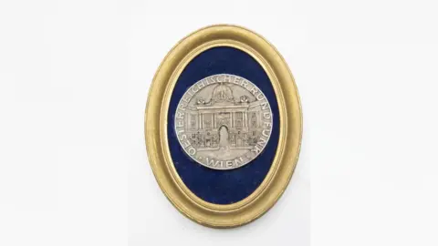 John Rolfe Auctions Pale gold medal with image of classical domed building on the front