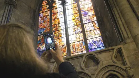 Durham Cathedral Woman takes photo of window on phone