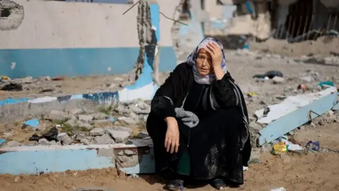 Reuters Una mujer sentada junto a un edificio destruido en Rafah, en el sur de la Franja de Gaza.  Foto: febrero de 2024