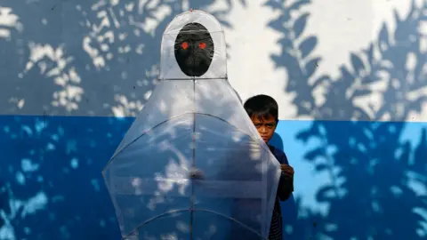 A child carries a kite depicting an Indonesian ghost