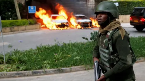 Reuters A policeman runs past burning cars at the scene where explosions and gunshots were heard at the Dusit hotel compound, in Nairobi, Kenya January 15, 2019.