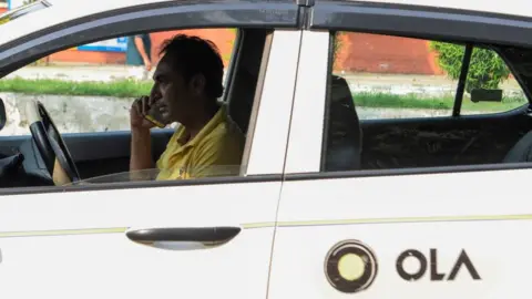 Getty Images An Ola cab driver talks on his mobile phone at a roadside in Amritsar