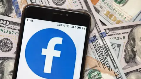 Getty Images Facebook logo on phone with dollar bills in background