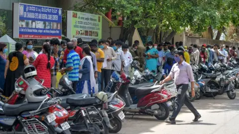 Getty Images People queue up outside a hospital in Bangalore