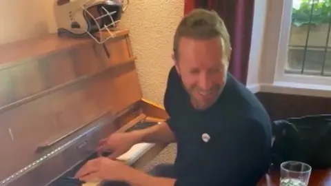 Coldplay's Chris Martin plays a pub piano