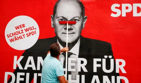 Reuters A placard of Olaf Scholz, candidate for Chancellor of Germany's Social Democratic party SPD is placed on a board for the September 26 German general elections in Bonn, Germany, September 20, 2021