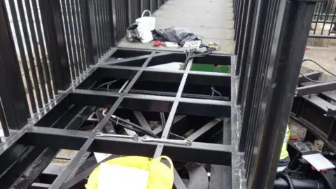 DoI A close up of the bridge deck, which has black large squares as part of the bridge deck has been removed.