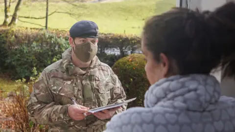 PA Media Soldier talks to resident on doorstep