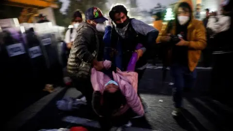 Reuters Members of the migrant caravan carry a fellow migrant who was injured when a crowd pushed against the police, who are preventing them from passing on the Mexico-Puebla highway, in Los Reyes La Paz, Mexico, December 12, 2021