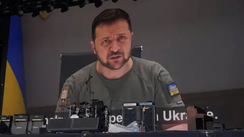 PA Media Ukrainian President Volodymyr Zelensky shown to the crowd at the Other Stage during the Glastonbury Festival