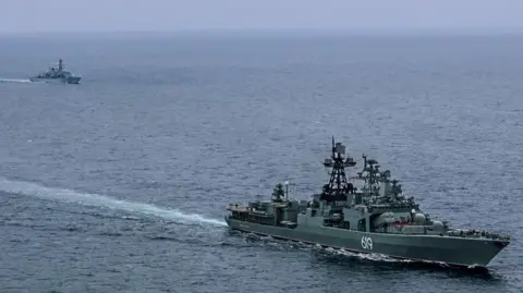 Royal Navy Image shows two ships out at sea. In the foreground is Russian warship RFN Severomorsk 619 and in the top left corner is Royal Navy vessel HMS Somerset
