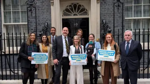Wera Hobhouse A collection of people including Bath MP Wera Hobhouse stand outside the door to 10 Downing Street. Several of them hold placards reading, "behind every statistic is a life" and "I support the national strategy to prevent eating disorder deaths".