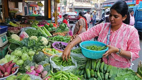 Getty Images A woman buying vegetables at a market